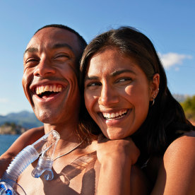 Woman with boyfriend smiling holding snorkel and scuba mask